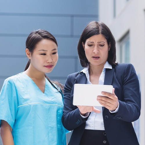A senior registered nurse guiding a licensed practical nurse using a tablet, showcasing the expertise and technology integration in our Licensed Practical Nurse (LPN) care.